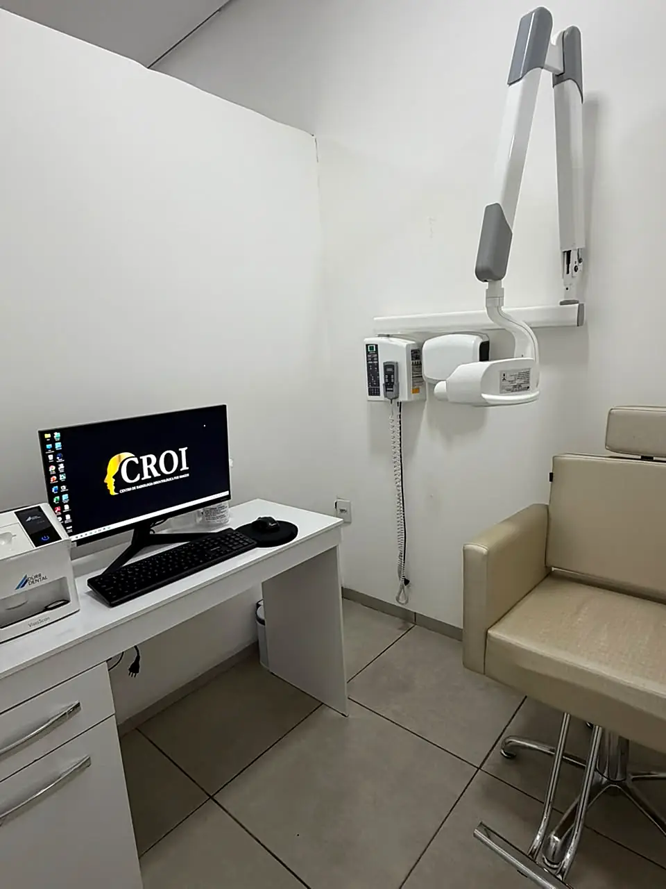 Sala de raio-x intraoral com aparelho de parede, computador e cadeira